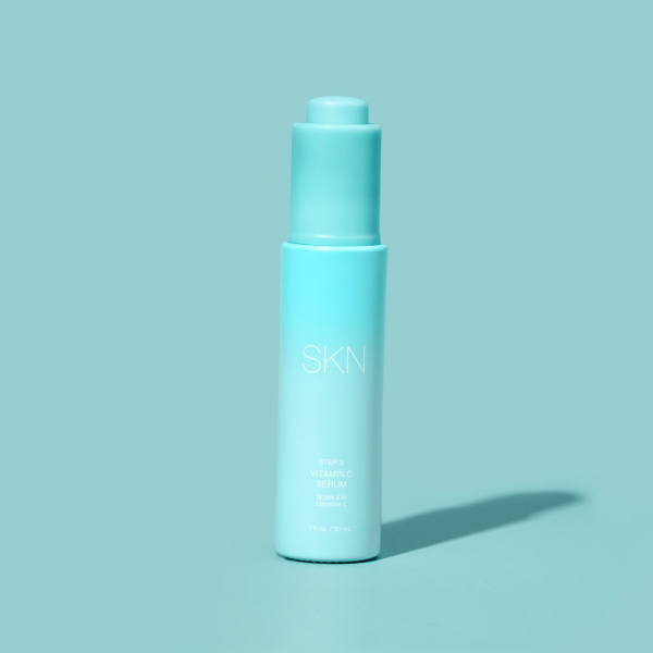 light blue bottle of SKN by Lori Harvey Vitamin C serum on a light blue background