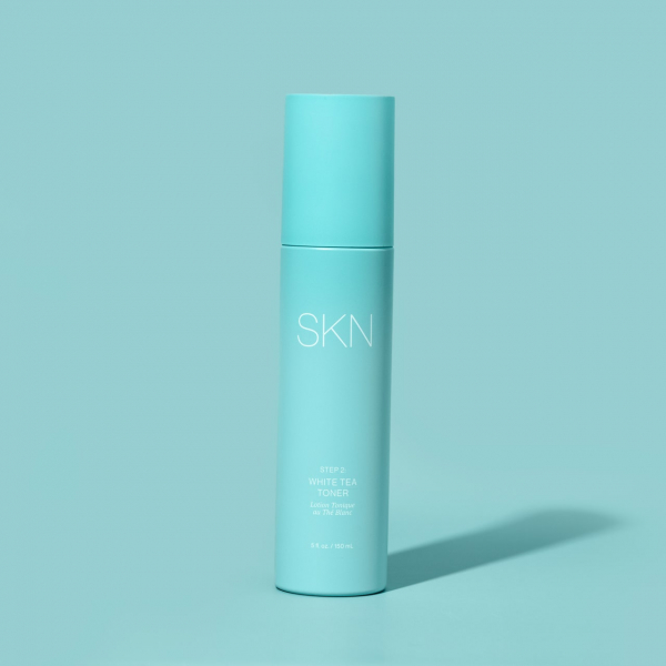 light blue bottle of SKN by Lori Harvey white tea toner on a light blue background